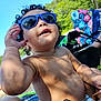 Romeo is registered to the contest to win money with this photo: toddler, child, sunglasses, curly_hair, outdoor, summer, sunny, blue_sky, baby, bare_chest, playful, hand, colorful_bag, nature, trees, relaxing, shade, diaper, person, closeup