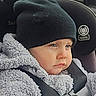 baby, child, car_seat, hat, coat, winter_clothing, seatbelt, closeup, face, blue_eyes, infant, warm, indoors, portrait, seat, profile, soft_texture, cute, expression, safety