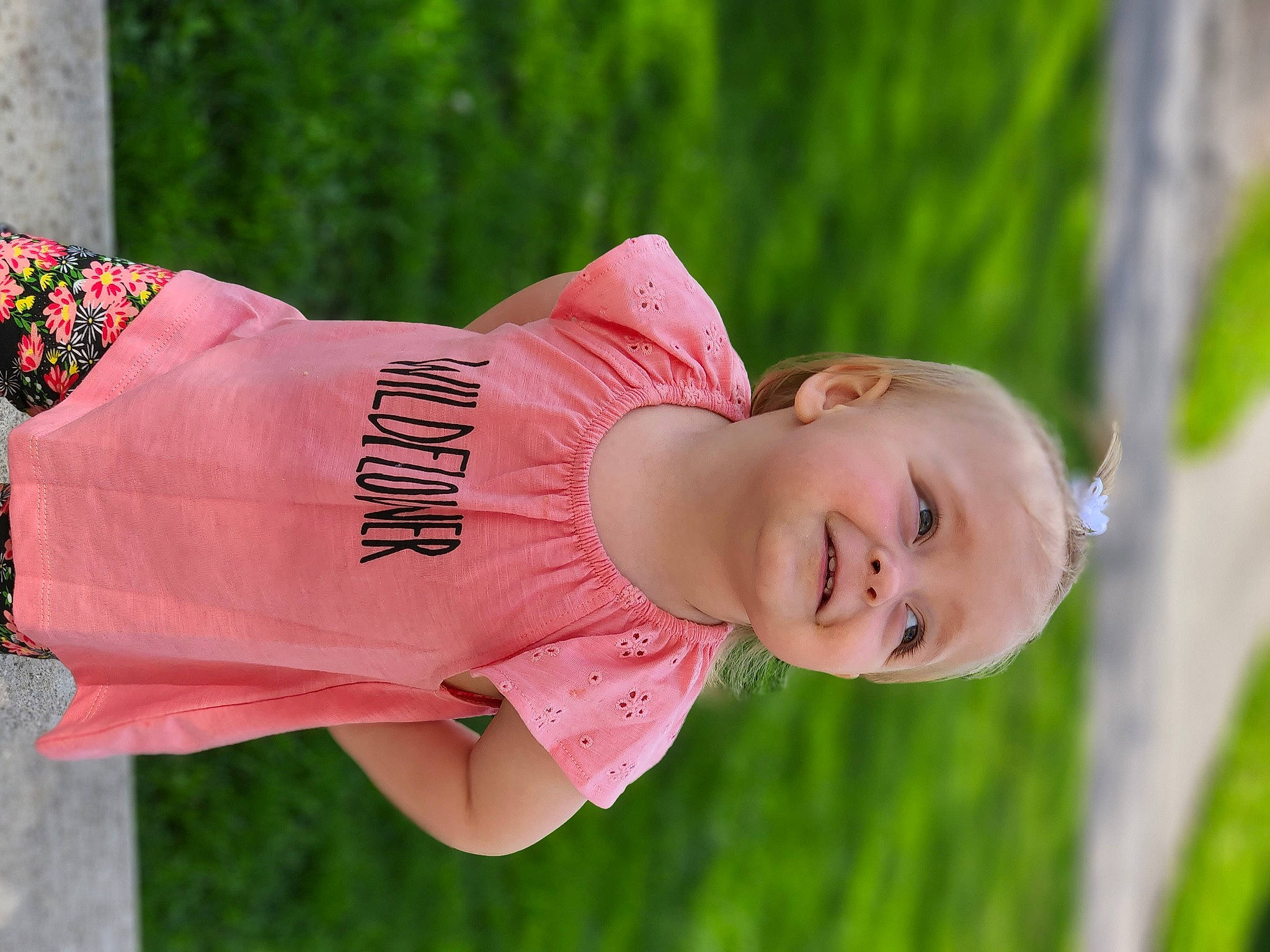 Kynzlee is registered to the contest to win money with this photo: abdomen, child, fun, grass, happy, jewellery, joy, leisure, lip, magenta, peach, people_in_nature, person, plant, portrait_photography, recreation, sitting, smile, t_shirt, toddler