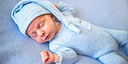 Tiarnán is registered to the contest to win money with this photo: baby, blanket, blue_clothing, blue_hat, child, closeup, cozy, cute, face, hand, headwear, indoors, infant, knitwear, newborn, peaceful, portrait, resting, sleeping, soft_texture