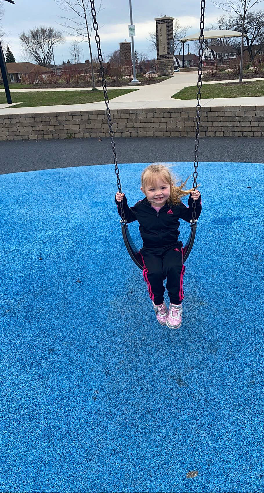 Ariana is registered to the contest to win money with this photo: asphalt, baby, blue, child, city, electric_blue, fun, grass, happy, joy, leisure, outdoor_play_equipment, outdoor_recreation, person, plant, play, playground, recreation, smile, swing