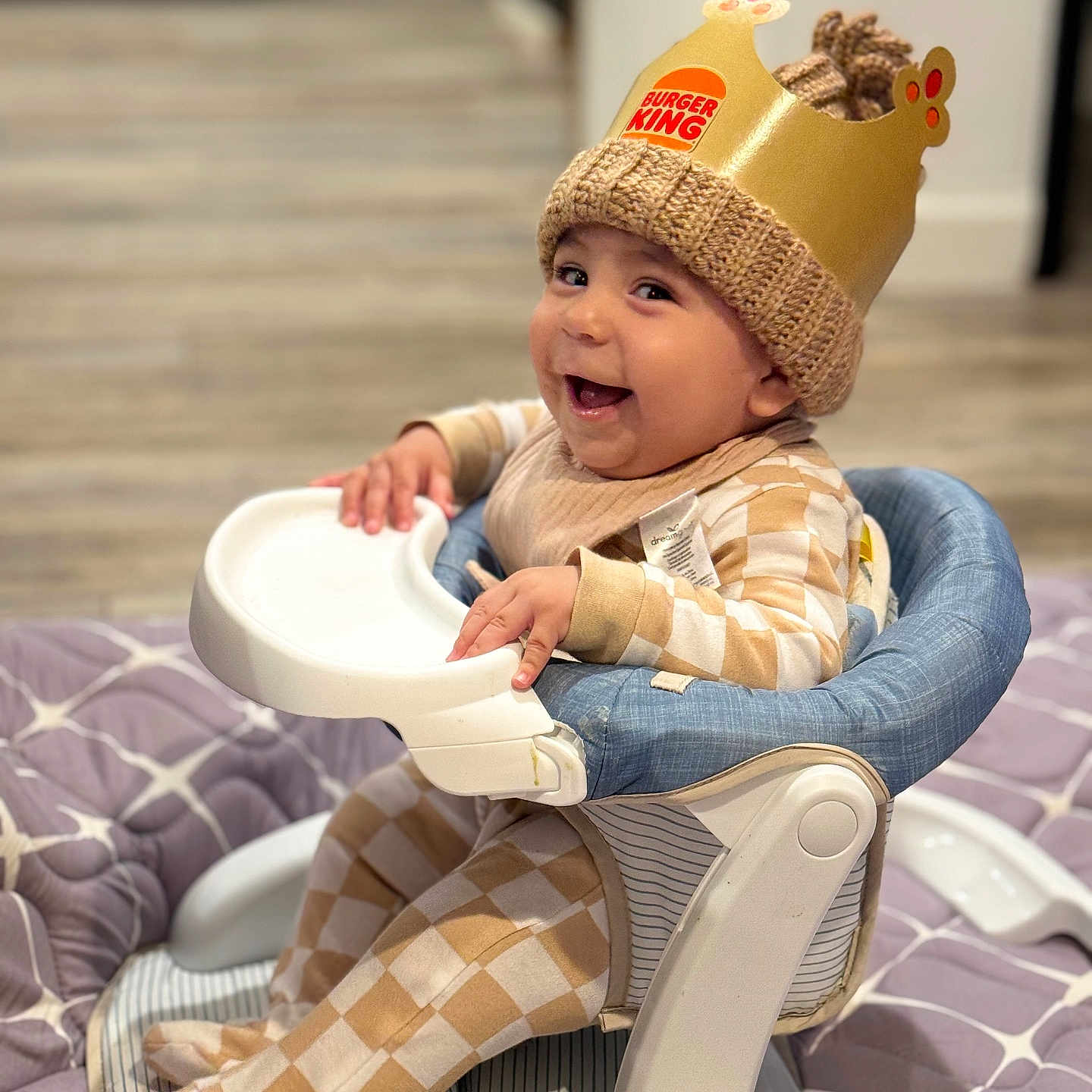 Azael joined the competition — help win amazing prizes! baby, baby_clothes, burger_king, cheerful, child, crown, cute, floor, footed_pajamas, happy, headwear, high_chair, indoor, infant, knit_hat, person, plaid_clothing, quilt, seat, smiling
