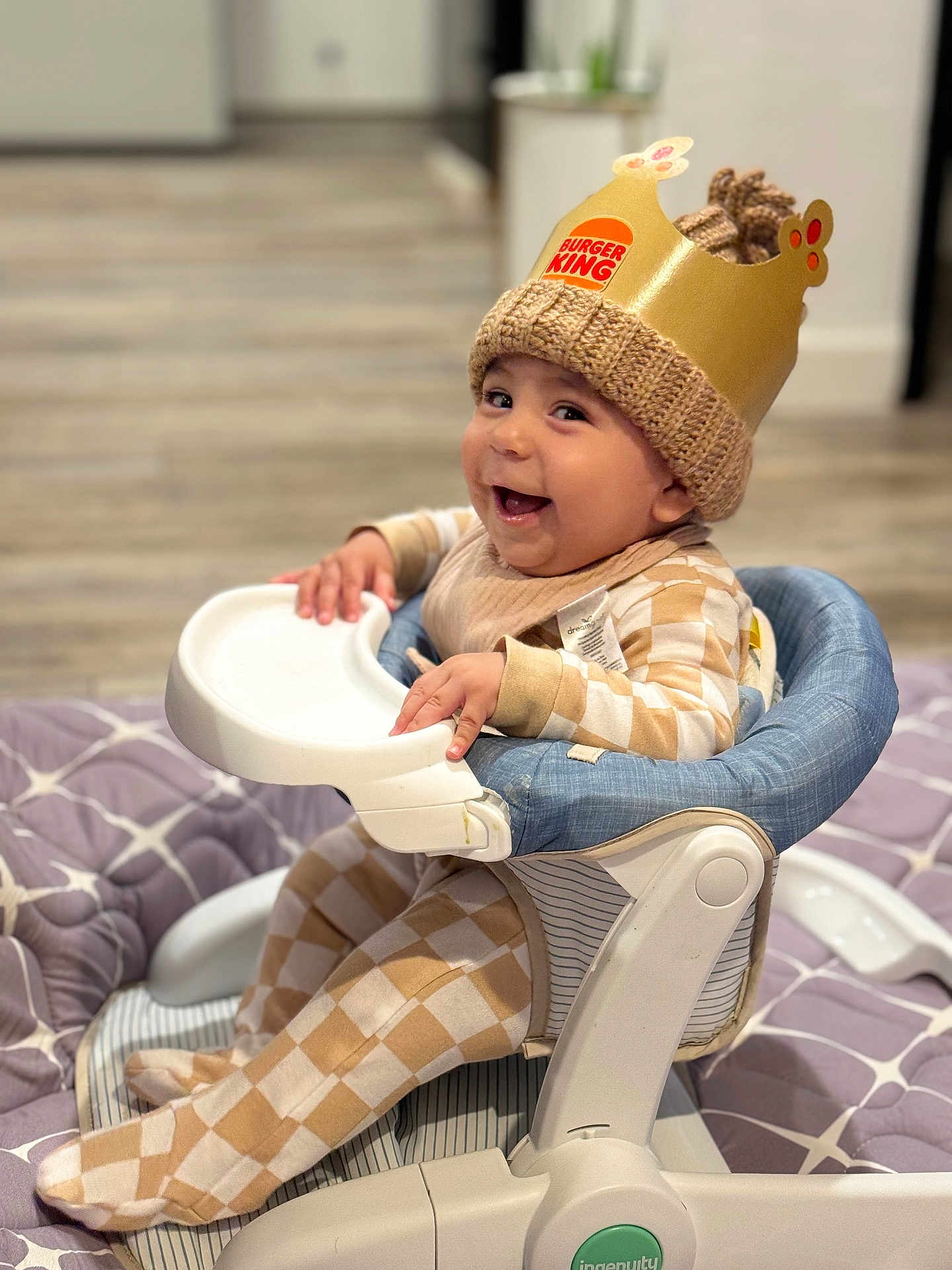 Azael joined the competition — help win amazing prizes! baby, child, high_chair, crown, burger_king, knit_hat, smiling, indoor, plaid_clothing, footed_pajamas, happy, person, seat, quilt, floor, baby_clothes, infant, cute, headwear, cheerful