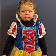 Mila a rejoint le concours — aidez-le/la à gagner de superbes lots ! child, girl, toddler, costume, snow_white_costume, dress, yellow_skirt, blue_bodice, red_trim, curly_hair, portrait, neutral_expression, standing, plain_background, long_sleeves, hands, fair_skin, closeup, sparkle, young_face