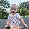 Miranda is registered to the contest to win money with this photo: baby, child, smiling, outdoor, trampoline, trees, sky, greenery, infant, onesie, happy, sitting, cute, nature, playtime, sunlight, portrait, young_child, person, daylight