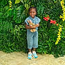 Emeri is registered to the contest to win money with this photo: child, smiling, denim_jumpsuit, plush_toy, bunny, greenery, leaves, flowers, yellow_flowers, red_flowers, sneakers, standing, indoor, portrait, happy, cute, person, hair_beads, tile_floor, colorful