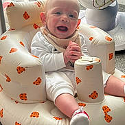 Tiaan is registered to the contest to win money with this photo: baby, infant, smile, happy, sitting, clapping, white_clothing, bib, inflatable_chair, tiger_pattern, indoor, carpet, toy, baby_chair, child, cute, comfort, playful, person, candid