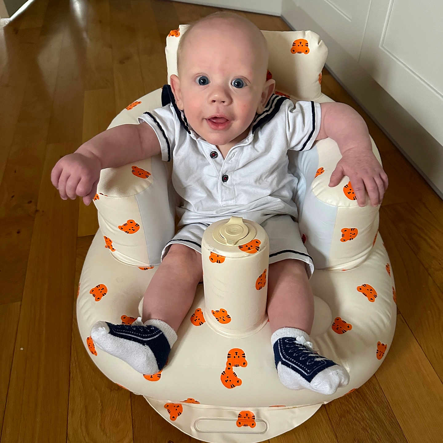 Tiaan is registered to the contest to win money with this photo: baby, child, comfort, curious, cute, expression, face, footwear, home, indoor, infant, inflatable_chair, joyful, person, plush, sitting, socks, tiger_pattern, white_clothing, wooden_floor