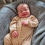 baby, infant, smile, onesie, striped_clothing, blanket, crib, sleepwear, cozy, happy, child, newborn, cute, soft_texture, furniture, bedroom, resting, comfort, portrait, indoor