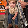 toddler, child, shopping_cart, boots, jeans, shirt, stain, hand, adult, store, floor, metal, retail, shopping, cute, baby, person, portrait, indoor, casual