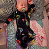 baby, sleeping, pacifier, pajamas, blanket, quilt, pillow, crib, infant, child, cozy, indoors, cute, peaceful, resting, footwear, patterned, colorful, soft, naptime