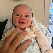 Luis participe au concours pour gagner de l'argent avec cette photo : baby, infant, smile, face, hand, blanket, clothing, person, indoor, soft_texture, happy, young_child, human, expression, close_up, skin, head, eyes, fingers, comfort
