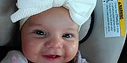 Autumn is registered to the contest to win money with this photo: baby, baby_girl, bow, car_seat, child, closeup, clothing, cute, face, hand, happy, headband, indoors, infant, person, portrait, safety, seatbelt, smile, young
