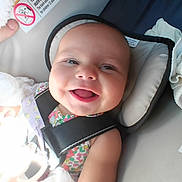 Autumn is registered to the contest to win money with this photo: baby, smiling, child, car_seat, seatbelt, blanket, infant, happy, face, head, clothing, soft_toy, person, indoors, closeup, cute, toddler, safety, seat, colorful