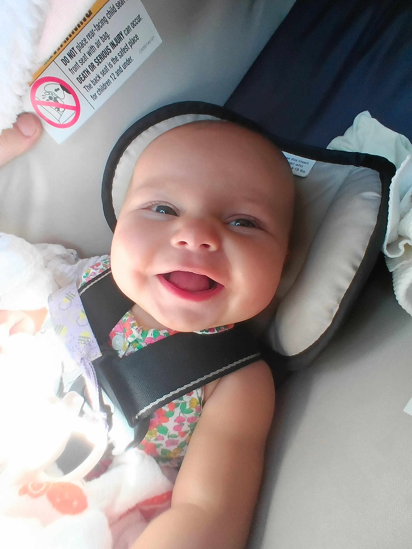 Autumn is registered to the contest to win money with this photo: baby, smiling, child, car_seat, seatbelt, blanket, infant, happy, face, head, clothing, soft_toy, person, indoors, closeup, cute, toddler, safety, seat, colorful