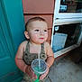 toddler, child, drink, cup, straw, romper, dinosaur_print, smile, outdoor, door, window, concrete, shoes, cute, person, young_child, holding, happy, casual, daylight