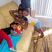 Devon joined the competition — help win amazing prizes! children, kids, group_portrait, siblings, couch, living_room, smiling, hugging, playful, indoor, family, child, toddler, casual_clothing, toy, blanket, window, vertical_blinds, carpet, sunlight
