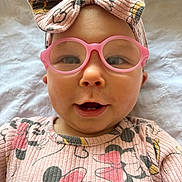 Serenity is registered to the contest to win money with this photo: baby, pink_glasses, headband, bow, cute, smiling, face, infant, clothing, minnie_mouse, pattern, pink, portrait, child, lying_down, white_background, happy, cute_expression, baby_girl, closeup