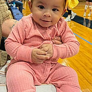 Skye joined the competition — help win amazing prizes! baby, child, pink_outfit, yellow_bow, headband, smile, hands, gymnasium, wooden_floor, people, background, seated, cushion, indoor, casual_clothing, curious_expression, infant, portrait, colorful, young_child