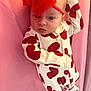 baby, infant, newborn, child, headband, red_bow, heart_print, onesie, pink_background, face, eyes, expression, hand, arm, blanket, fabric, lying_down, portrait, cute, clothing