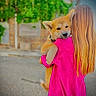 Bella participe au concours pour gagner de l'argent avec cette photo : dog, person, holding, pink_clothing, outdoor, street, fur, pet, animal, back_view, greenery, blurred_background, cute, companion, young_dog, canine, affection, casual, daytime, urban
