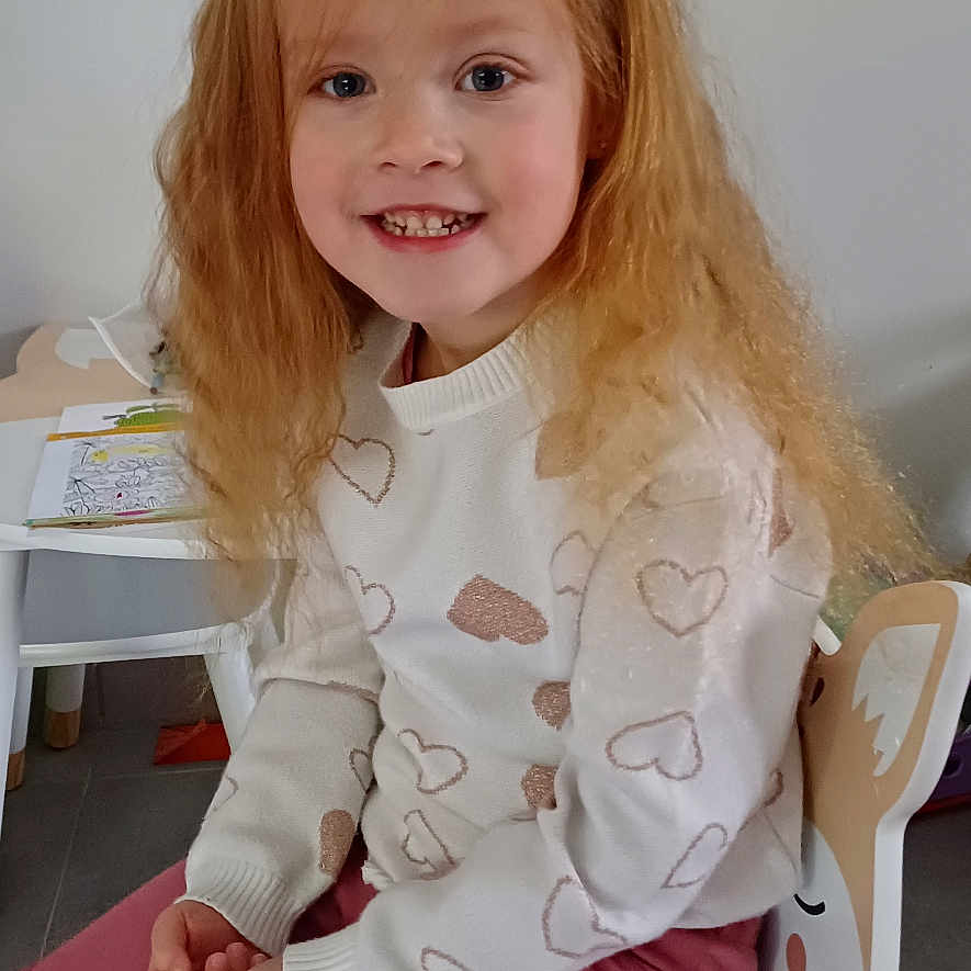 Léa participe au concours pour gagner de l'argent avec cette photo : bodypart, child, clothing, face, female, finger, furniture, girl, hand, happy, head, longsleeve, pants, person, photography, portrait, sitting, sleeve, smile, wood