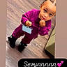 Sevyn joined the competition — help win amazing prizes! badge, big_eyes, casual_clothing, child, curious_expression, cute, floor, green_couch, hair_beads, holding_object, indoor, looking_up, person, portrait, purple_outfit, standing, toddler, toys, wood_floor, young_child