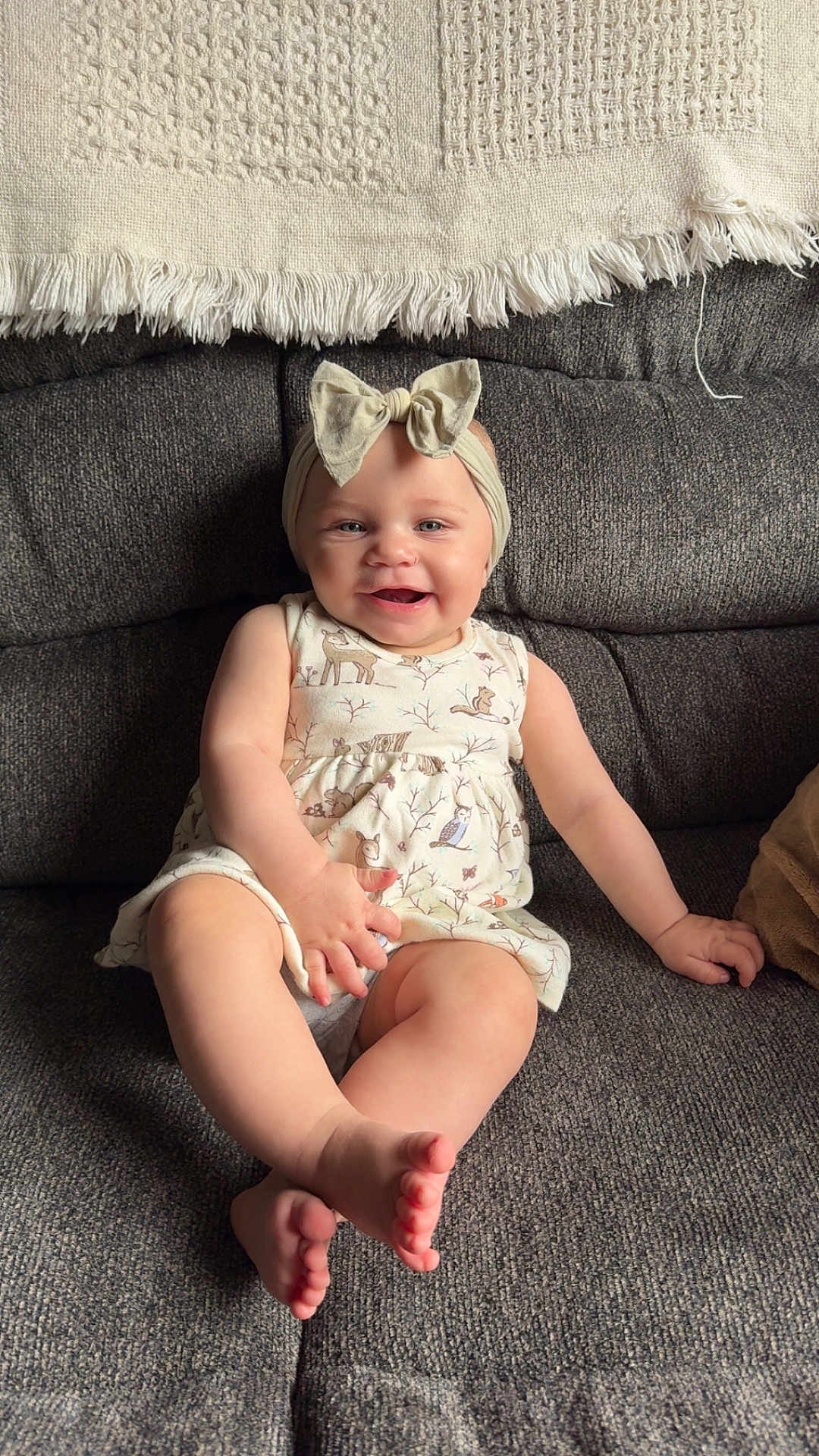 Ridgley is registered to the contest to win money with this photo: baby, child, smiling, sitting, couch, dress, bow, headband, indoor, happy, person, furniture, foot, hand, face, skin, comfort, home, infant, cute