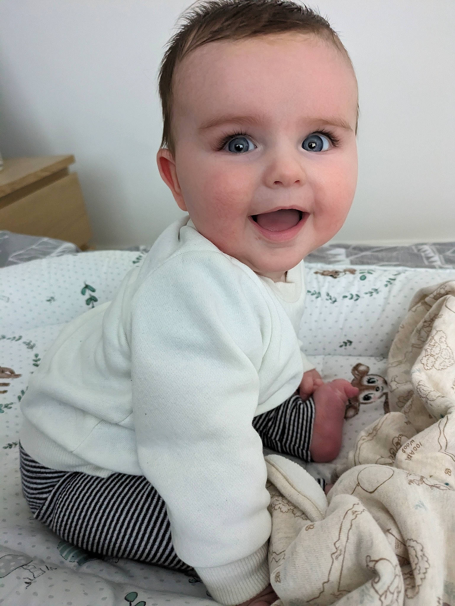 George is registered to the contest to win money with this photo: baby, baby_toddler_clothing, cheek, child, comfort, eye, flooring, happy, head, iris, joy, linens, lip, nose, pattern, person, sitting, skin, sleeve, smile