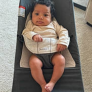 Rayna is registered to the contest to win money with this photo: baby, infant, bouncer, babybjorn, curly_hair, indoor, carpet, clothing, person, face, legs, feet, hand, expression, child, cute, relaxing, seat, furniture, home