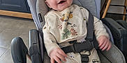 Noé participe au concours pour gagner de l'argent avec cette photo : baby, child, car_seat, bib, smiling, indoor, kitchen, blue_cabinet, plant, floor_tile, clothing, seatbelt, happy, person, infant, footed_pajamas, baby_girl, baby_boy, cute, home