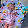 Leylanie is registered to the contest to win money with this photo: baby, infant, smiling, onesie, pacifier, colorful, geometric_pattern, cushion, toy, happy, playful, indoor, child, cute, cheerful, person, clothing, fabric, face, hands