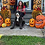 woman, dog, puppy, porch, pumpkin, halloween, flowers, smiling, steps, fall, decorations, grass, outdoor, curly_hair, black_dog, orange, festive, jack_o_lantern, holiday, happy