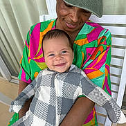 Callum joined the competition — help win amazing prizes! baby, infant, adult, smile, holding, checkered_outfit, colorful_shirt, cap, sunglasses, portrait, bench, porch, outdoor, happy, closeup, family, eyes, zipper, seated, skin