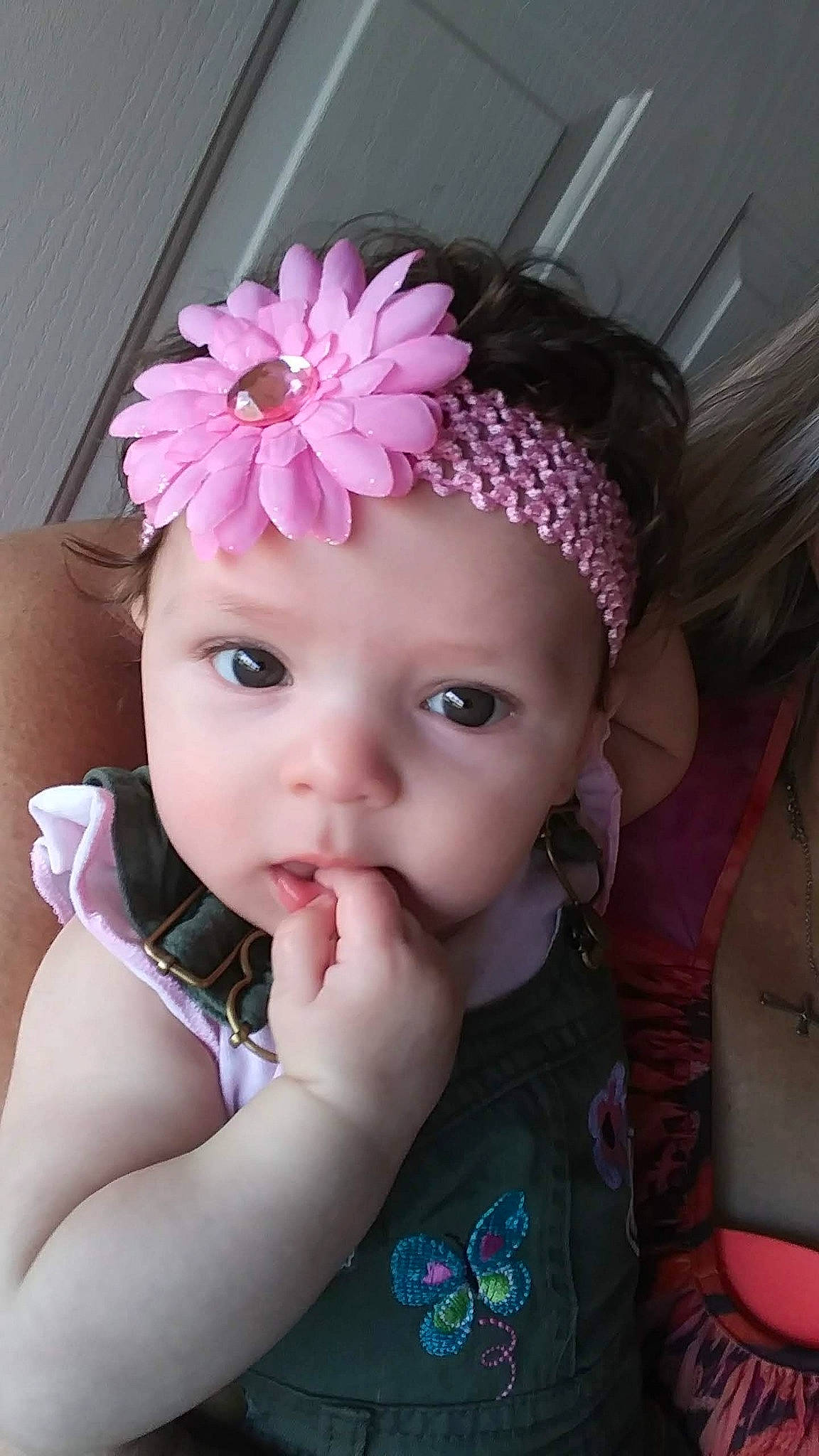 Ela is registered to the contest to win money with this photo: baby, brown_hair, cheek, child, child_model, face, fashion_accessory, flower, hair_accessory, headband, headgear, headpiece, person, petal, pink, plant, skin, smile, toddler