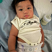 Kairo is registered to the contest to win money with this photo: baby, infant, diaper, mickey_mouse, simba, milk_bottle, bed, blanket, clothing, cute, person, face, hair, lying_down, indoors, child, skin, expression, hand, toddler