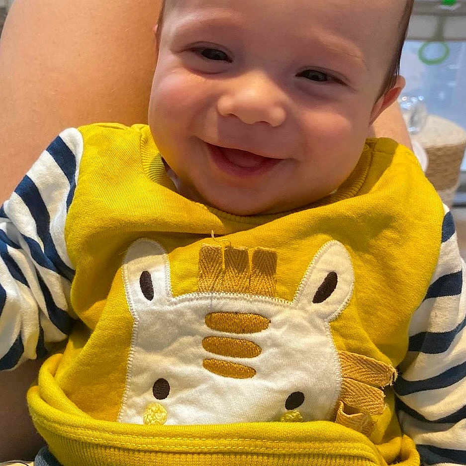 Titouan a rejoint le concours — aidez-le/la à gagner de superbes lots ! baby, blue_pants, casual, child, clothing, cozy, cute, face, giraffe_design, happy, indoor, infant, lap, person, portrait, seated, smiling, striped_sleeves, warm_colors, yellow_sweater