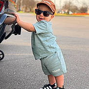 Marsel joined the competition — help win amazing prizes! child, toddler, baby, sunglasses, cap, hat_with_text, car, bumper, parking_lot, pavement, shorts, adidas, sandals, smile, standing, leaning, outdoor, casual_clothing, portrait, accessory