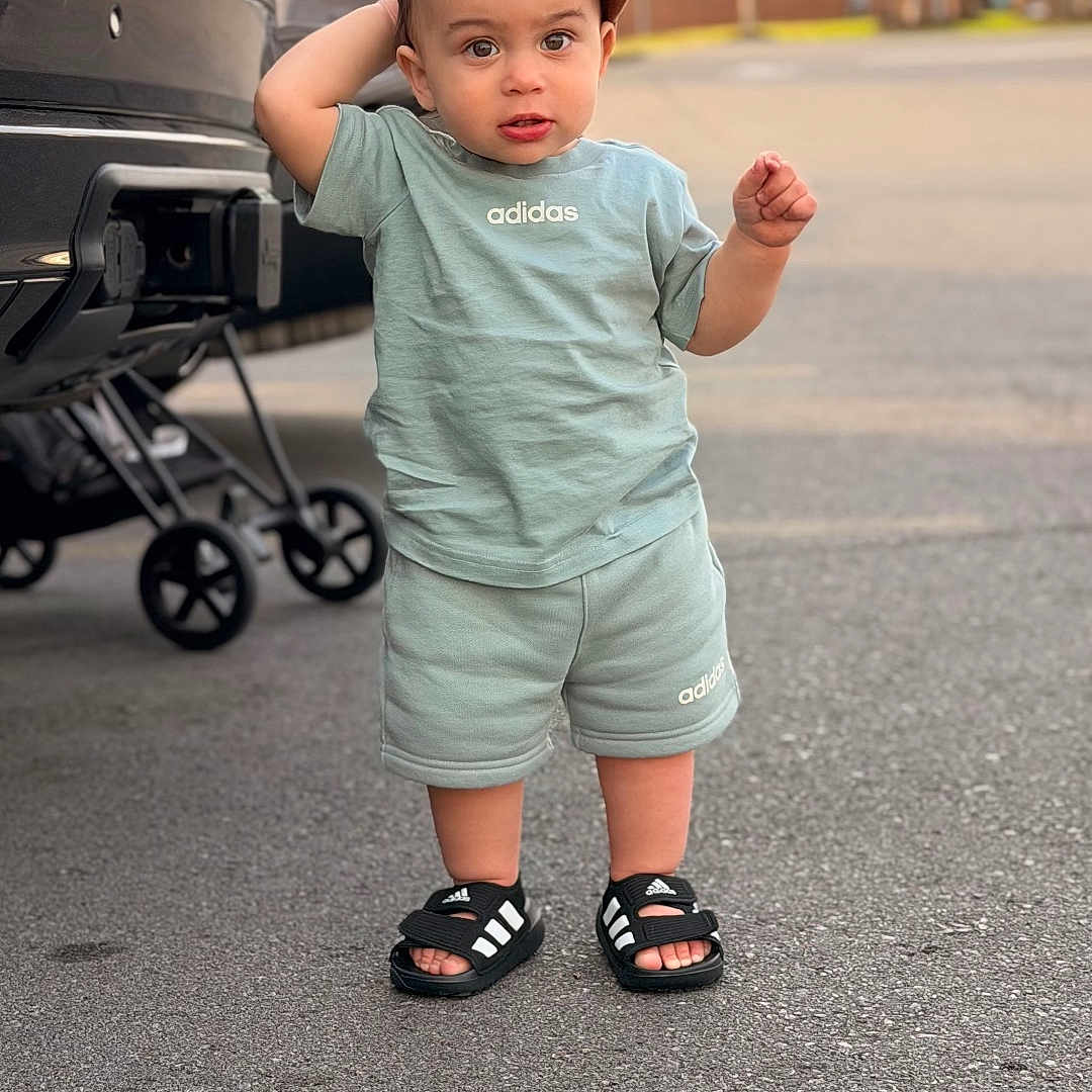 Marsel joined the competition — help win amazing prizes! adidas, adorable, baby, baseball_cap, cap, car, casual, child, clothing, face, outdoors, outfit, parking_lot, pavement, sandals, shoes, smile, standing, stroller, toddler