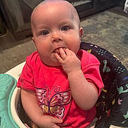 Summer is registered to the contest to win money with this photo: baby, infant, child, pink_shirt, butterfly, baby_walker, indoor, carpet, furniture, hand_in_mouth, cute, seated, playful, person, young_child, face, eyes, head, clothing, home