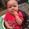baby, infant, child, pink_shirt, butterfly, baby_walker, indoor, carpet, furniture, hand_in_mouth, cute, seated, playful, person, young_child, face, eyes, head, clothing, home