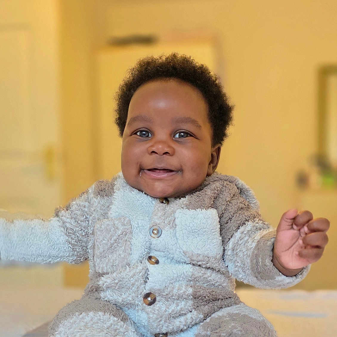 Rukudzo Wesley is registered to the contest to win money with this photo: baby, bed, child, cozy_clothing, curly_hair, cute, face, feet, fuzzy_outfit, hands, happy, home, indoors, infant, person, portrait, sitting, smiling, soft_texture, warm_lighting