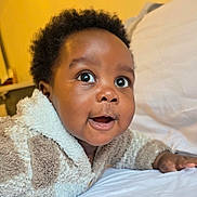 Rukudzo Wesley is registered to the contest to win money with this photo: baby, child, infant, face, eyes, smile, expression, bed, blanket, clothing, jacket, fur, texture, indoors, person, cute, happy, portrait, skin, young