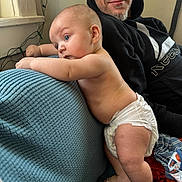Westley is registered to the contest to win money with this photo: baby, diaper, man, hoodie, couch, indoor, curious, smile, skin, blue, texture, person, infant, child, casual, adult, furniture, home, light, relax