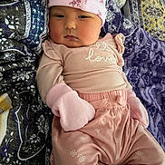 Jasmine is registered to the contest to win money with this photo: baby, infant, pink_clothing, mittens, hat, blanket, pattern, face, person, cute, child, sleepwear, fashion, portrait, lying_down, soft_texture, home, cozy, newborn, expression