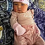 baby, infant, pink_clothing, mittens, hat, blanket, pattern, face, person, cute, child, sleepwear, fashion, portrait, lying_down, soft_texture, home, cozy, newborn, expression