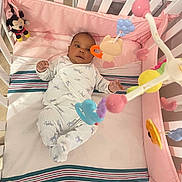 Aleah is registered to the contest to win money with this photo: baby, crib, mobile, toy, mickey_mouse, pink, bedding, infant, sleepwear, striped_blanket, soft_toys, child, indoors, cute, resting, floor_tiles, pajamas, baby_girl, baby_boy, newborn
