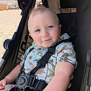 Tucker joined the competition — help win amazing prizes! baby, child, stroller, blue_eyes, smile, shirt, patterned_clothing, seatbelt, outdoor, beach, sunny, rosy_cheeks, infant, cute, portrait, summer, happy, person, closeup, casual