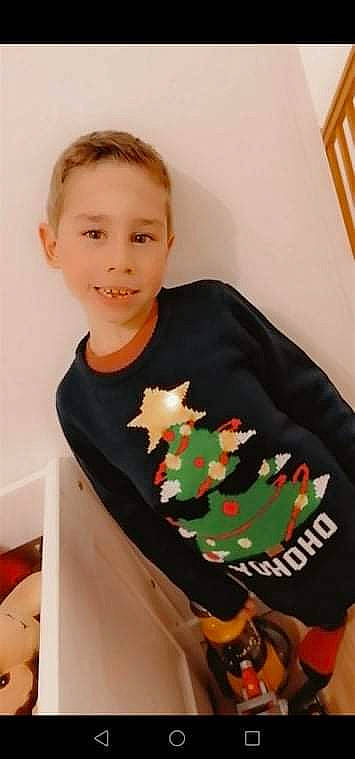 Ethan participe au concours pour gagner de l'argent avec cette photo : carmine, child, christmas, christmas_decoration, christmas_ornament, christmas_stocking, elbow, event, fictional_character, holiday, joy, neck, ornament, pattern, person, room, sitting, sleeve, smile, t_shirt