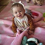 Kayden participe au concours pour gagner de l'argent avec cette photo : baby, child, smiling, pink_blanket, toy, stuffed_animal, dog, indoor, floor, happy, cute, playful, infant, person, pet, tiled_floor, clothing, home, crawling, young